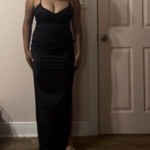 This sleek black dress features delicate spaghetti straps and a thigh-high slit.